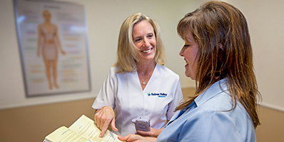 Female doctor showing a female patient in blue something in a book
